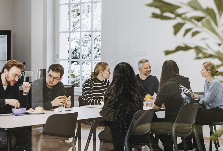 Angelbird employees seated around a table in a collaborative meeting, sharing ideas and building team connection.